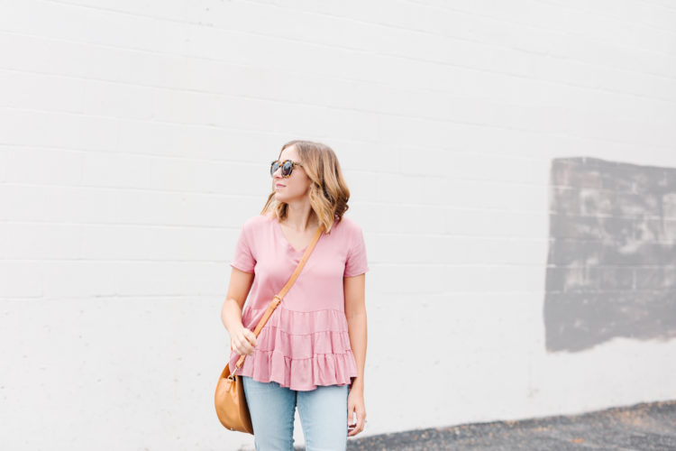 A casual feminine look full of Fall's biggest trends - blush top, step hem jeans, a round bag, and block heels.